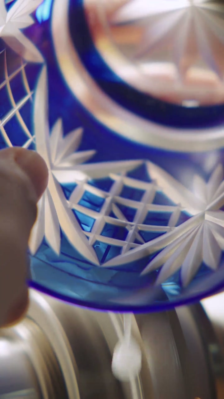 The marked glass held by hand against a rotating cutting wheel